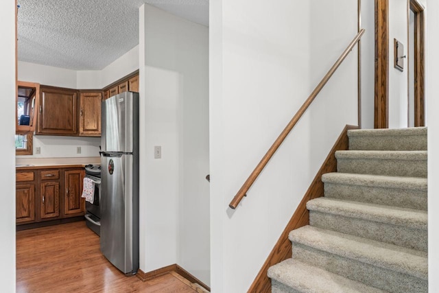 1719 Buckingham Path, Faribault, MN 55021 - kitchen with stainless steel appliances, light wood finished floors, a textured ceiling, light countertops, and baseboards