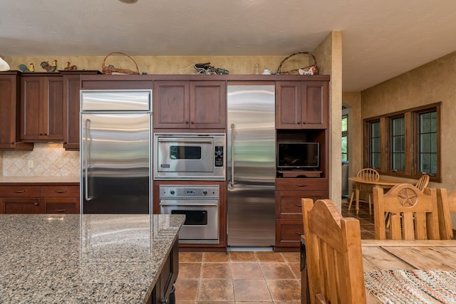 56273 185th Ln, Rapidan Twp, MN 56037 - kitchen featuring appliances with stainless steel finishes, decorative backsplash, light stone countertops, and stone finish floors