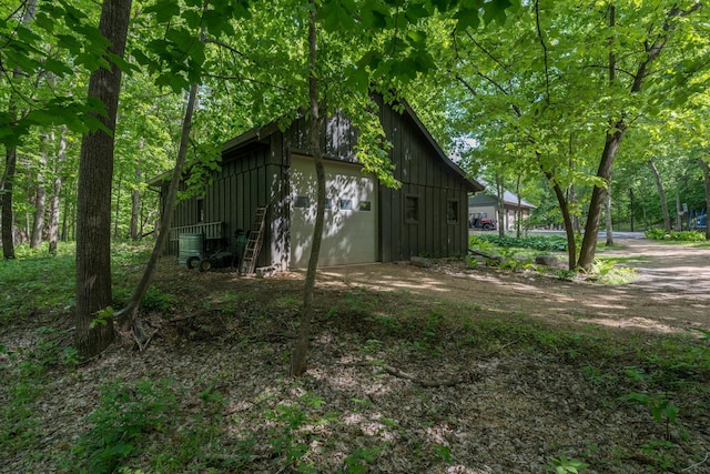 56273 185th Ln, Rapidan Twp, MN 56037 - view of home's exterior with board and batten siding, a garage, dirt driveway, and an outbuilding