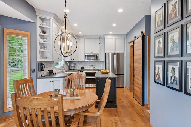 2392 Molnau Ct, Chaska, MN 55318 - dining space with a chandelier, a barn door, light wood-style flooring, recessed lighting, and baseboards
