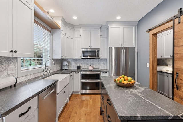 2392 Molnau Ct, Chaska, MN 55318 - kitchen with appliances with stainless steel finishes, a sink, a center island, tasteful backsplash, and a barn door