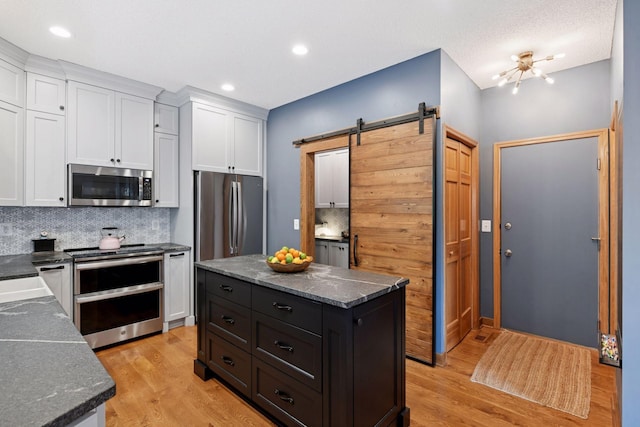 2392 Molnau Ct, Chaska, MN 55318 - kitchen with stainless steel appliances, a barn door, light wood finished floors, white cabinets, and backsplash