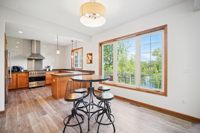 1106 Shumway Ct, Faribault, MN 55021 - kitchen with appliances with stainless steel finishes, wall chimney range hood, a sink, light wood-style flooring, and dark countertops
