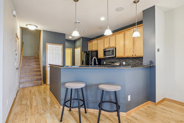 1964 Commonwealth Blvd Unit 5, Chanhassen, MN 55317 - kitchen with stainless steel microwave, black refrigerator with ice dispenser, a peninsula, light wood finished floors, and a textured ceiling