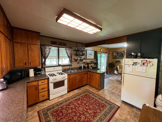 355 20th St SW, Benson, MN 56215 - kitchen featuring white appliances, dark countertops, healthy amount of natural light, wood walls, and crown molding