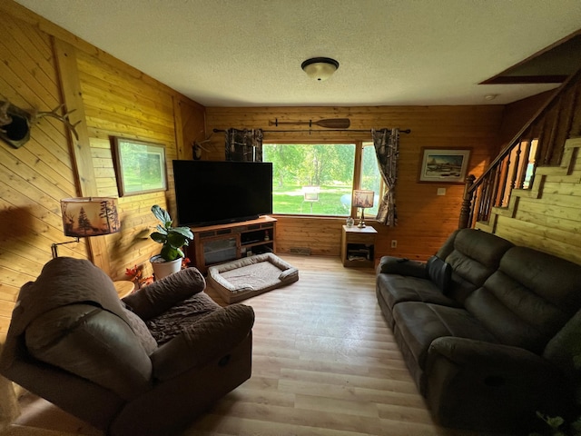 355 20th St SW, Benson, MN 56215 - living area with a textured ceiling, wooden walls, light wood-style floors, and stairs