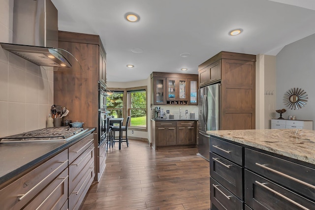 27806 Sundance Ln, Cold Spring, MN 56320 - kitchen with wall chimney exhaust hood, stainless steel appliances, tasteful backsplash, dark stone countertops, and glass insert cabinets