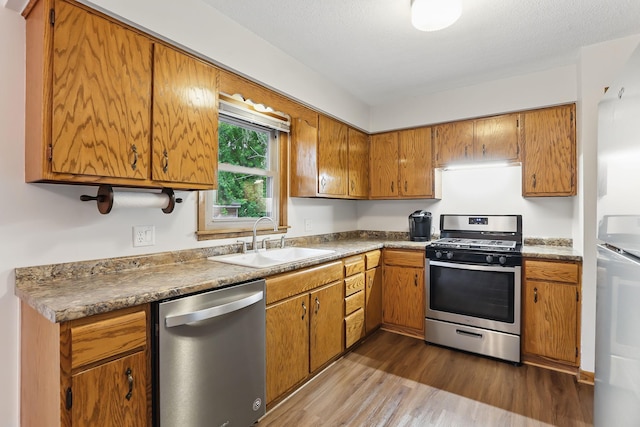 1202 Lyn Way, Hastings, MN 55033 - kitchen featuring appliances with stainless steel finishes, a sink, dark wood-type flooring, and brown cabinetry