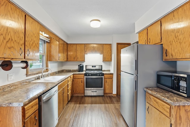 1202 Lyn Way, Hastings, MN 55033 - kitchen with stainless steel appliances, a sink, wood finished floors, and brown cabinets
