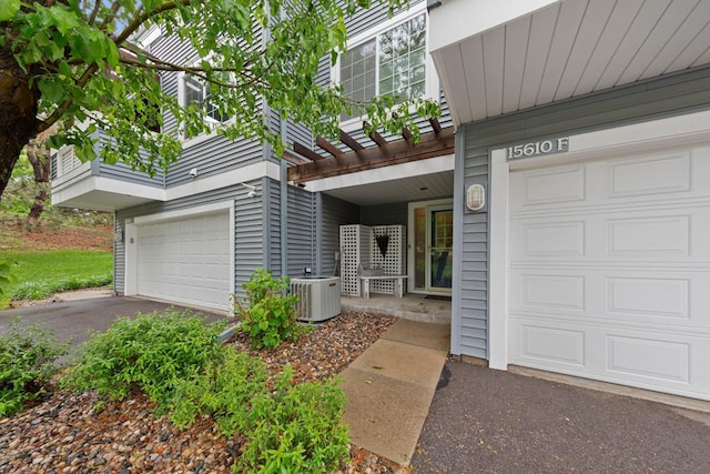 15610 24th Ave N Unit F, Plymouth, MN 55447 - view of exterior entry featuring central AC unit, an attached garage, and driveway