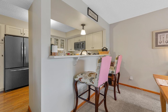 15610 24th Ave N Unit F, Plymouth, MN 55447 - kitchen featuring stainless steel appliances, a breakfast bar, baseboards, white cabinets, and light countertops