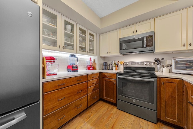 15610 24th Ave N Unit F, Plymouth, MN 55447 - kitchen featuring stainless steel appliances, light countertops, light wood-style floors, and glass insert cabinets