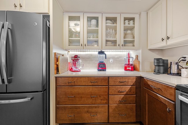 15610 24th Ave N Unit F, Plymouth, MN 55447 - kitchen featuring freestanding refrigerator, tasteful backsplash, glass insert cabinets, and white cabinetry