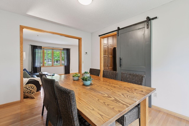 1502 Rocky Ln, Eagan, MN 55122 - dining room with light wood-style floors, a barn door, baseboards, and a textured ceiling