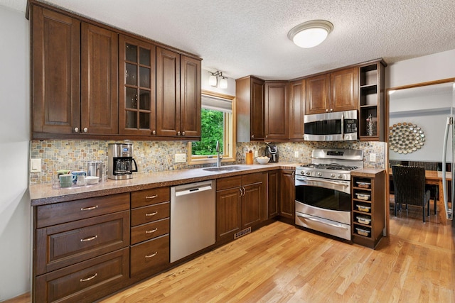 1502 Rocky Ln, Eagan, MN 55122 - kitchen with stainless steel appliances, a sink, light wood finished floors, a textured ceiling, and tasteful backsplash