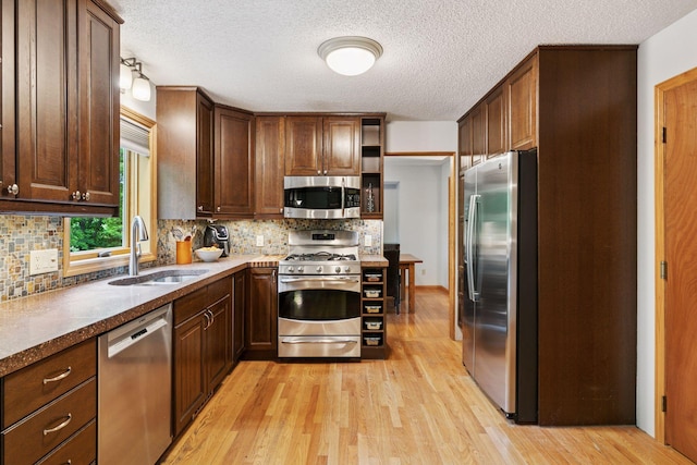 1502 Rocky Ln, Eagan, MN 55122 - kitchen with stainless steel appliances, a sink, light wood finished floors, tasteful backsplash, and a textured ceiling