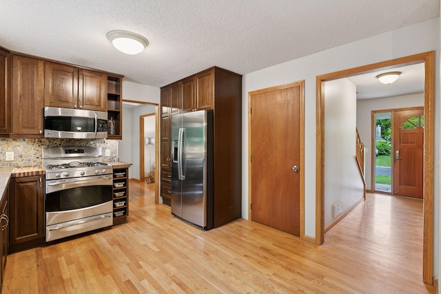 1502 Rocky Ln, Eagan, MN 55122 - kitchen with stainless steel appliances, light wood-type flooring, light countertops, decorative backsplash, and a textured ceiling