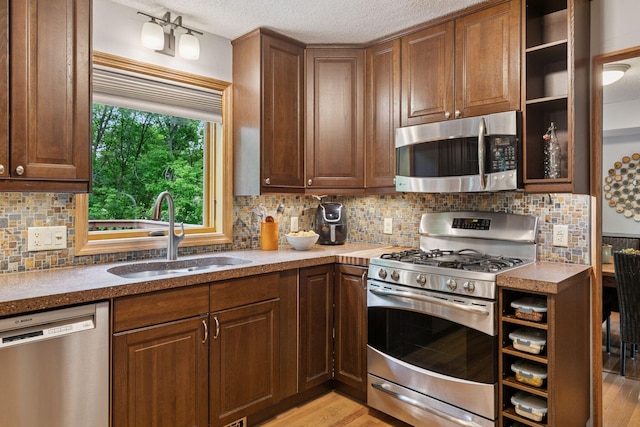 1502 Rocky Ln, Eagan, MN 55122 - kitchen with appliances with stainless steel finishes, a sink, open shelves, a textured ceiling, and light wood finished floors