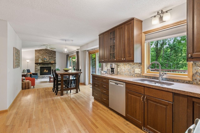1502 Rocky Ln, Eagan, MN 55122 - kitchen with dishwasher, a sink, a fireplace, light wood finished floors, and decorative backsplash
