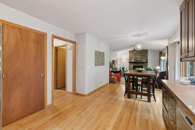 1502 Rocky Ln, Eagan, MN 55122 - dining room with light wood-style flooring, a fireplace, lofted ceiling, a textured ceiling, and baseboards