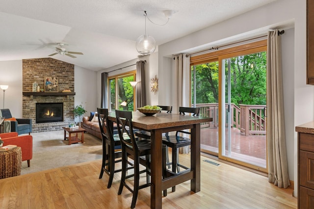 1502 Rocky Ln, Eagan, MN 55122 - dining area featuring ceiling fan, a fireplace, lofted ceiling, and light wood-type flooring