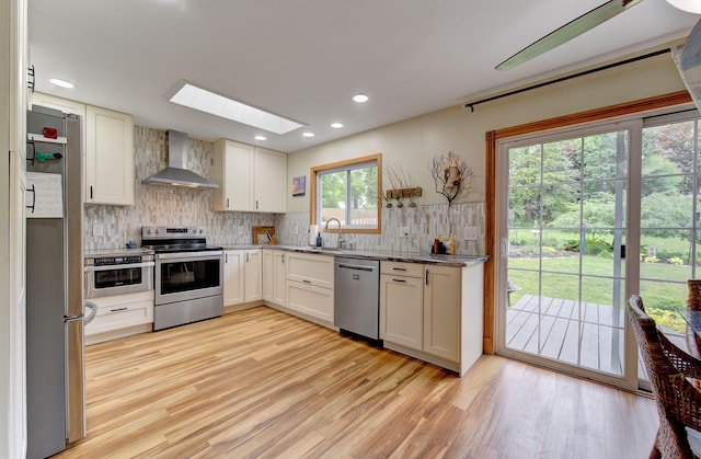 3021 Crescent Ln NW, Rochester, MN 55901 - kitchen with wall chimney range hood, appliances with stainless steel finishes, a skylight, backsplash, and a sink