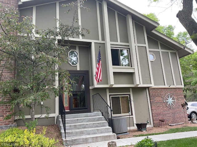 6800 Buckingham Ct, Woodbury, MN 55125 - view of exterior entry featuring stucco siding, cooling unit, and brick siding
