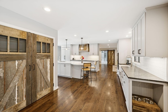 200 Marie Ave W, West Saint Paul, MN 55118 - kitchen with a barn door, a kitchen island, tasteful backsplash, recessed lighting, and dark wood-style flooring