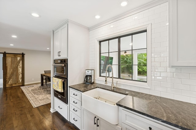 200 Marie Ave W, West Saint Paul, MN 55118 - kitchen with a barn door, stainless steel double oven, tasteful backsplash, dark wood-style flooring, and dark stone countertops