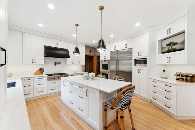 6539 Orchard Ridge Trl, Woodbury, MN 55129 - kitchen with under cabinet range hood, built in appliances, a breakfast bar area, light wood-style flooring, and recessed lighting