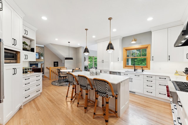 6539 Orchard Ridge Trl, Woodbury, MN 55129 - kitchen featuring a sink, a stone fireplace, light wood-type flooring, appliances with stainless steel finishes, and white cabinetry