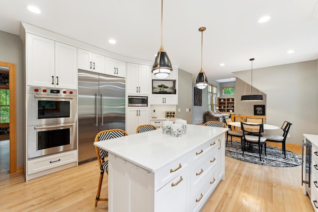 6539 Orchard Ridge Trl, Woodbury, MN 55129 - kitchen with built in appliances, light wood-style flooring, white cabinets, pendant lighting, and light countertops
