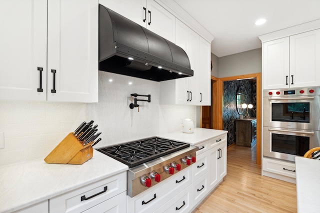 6539 Orchard Ridge Trl, Woodbury, MN 55129 - kitchen with under cabinet range hood, appliances with stainless steel finishes, light countertops, white cabinetry, and decorative backsplash