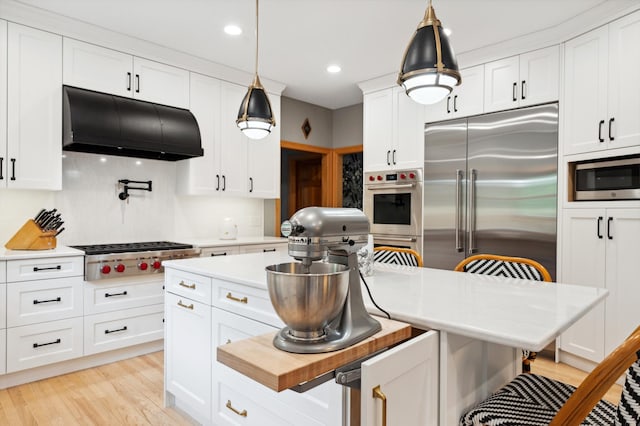6539 Orchard Ridge Trl, Woodbury, MN 55129 - kitchen featuring stainless steel appliances, under cabinet range hood, a kitchen breakfast bar, decorative light fixtures, and white cabinets