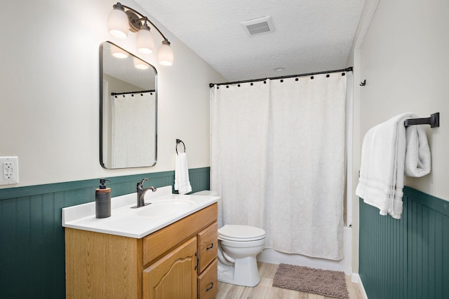 1305 Unity Ave N, Golden Valley, MN 55422 - bathroom featuring vanity, wainscoting, toilet, a textured ceiling, and wood finished floors