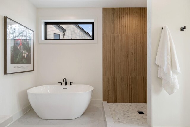 bathroom with marble finish floors, a freestanding tub, baseboards, and a shower