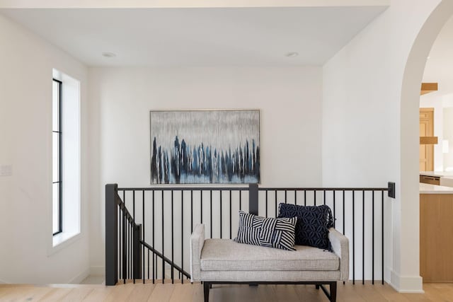 living area featuring arched walkways, wood finished floors, and baseboards