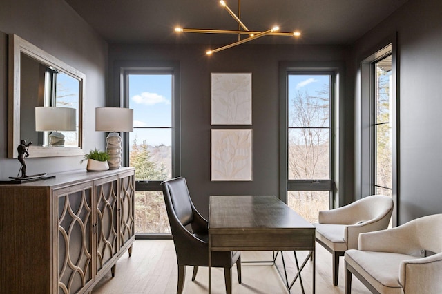 dining space featuring a chandelier, light wood-type flooring, and healthy amount of natural light