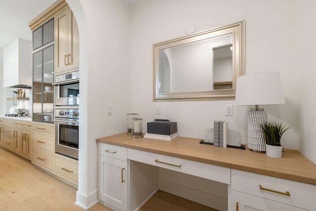 kitchen with light wood-style flooring, light countertops, stainless steel appliances, and arched walkways