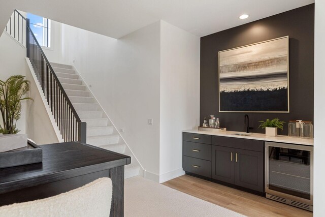indoor wet bar featuring beverage cooler, light wood-style flooring, stairway, recessed lighting, and baseboards