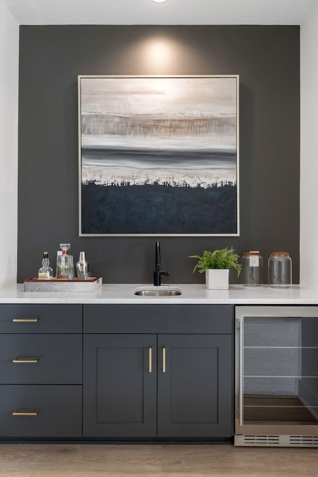 indoor wet bar featuring wine cooler and light wood-style flooring