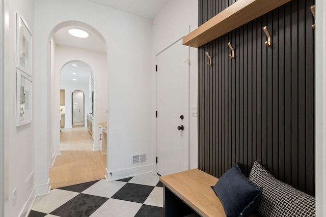 mudroom featuring tile patterned floors, arched walkways, and baseboards