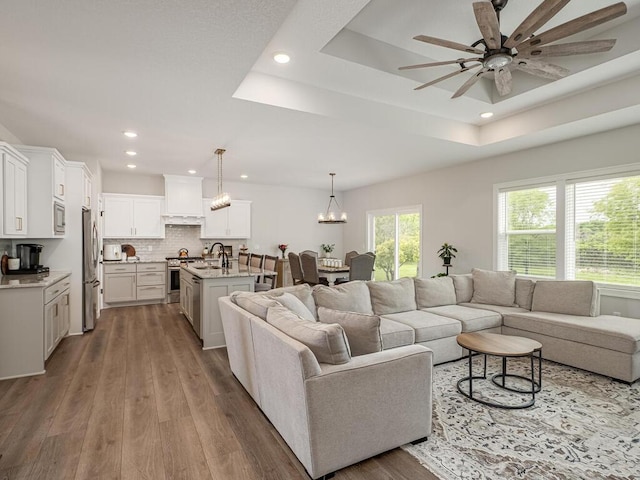 3309 171st Ave NE, Ham Lake, MN 55304 - living room with ceiling fan, recessed lighting, wood finished floors, a tray ceiling, and a chandelier