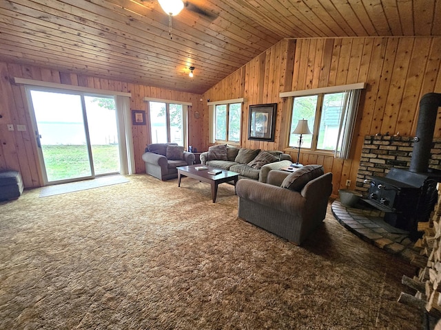 27042 Bluebill Point Rd, Garrison, MN 56450 - carpeted living room featuring vaulted ceiling, wooden walls, wood ceiling, a wood stove, and a ceiling fan