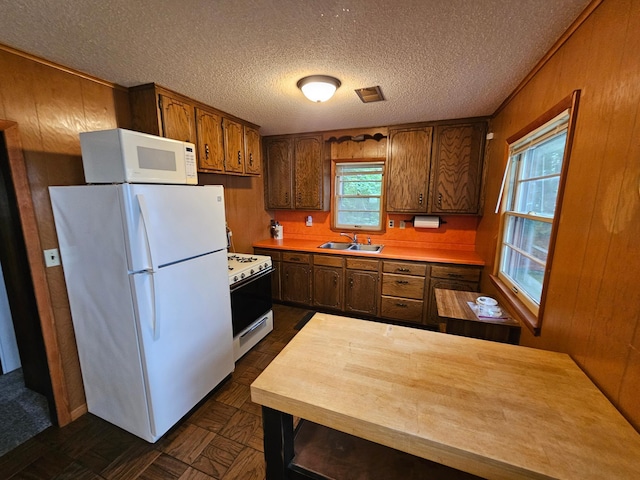 27042 Bluebill Point Rd, Garrison, MN 56450 - kitchen featuring white appliances, light countertops, a sink, a textured ceiling, and wooden walls