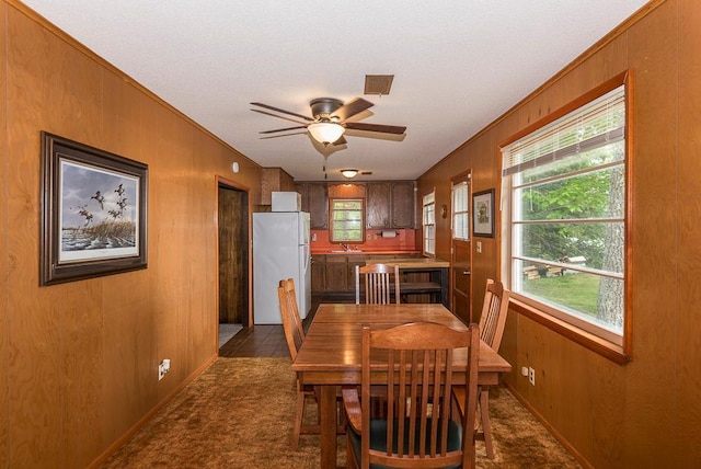 27042 Bluebill Point Rd, Garrison, MN 56450 - dining room with crown molding, ceiling fan, wood walls, baseboards, and dark colored carpet