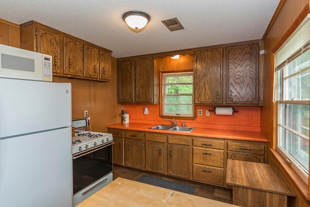 27042 Bluebill Point Rd, Garrison, MN 56450 - kitchen featuring white appliances, a sink, brown cabinets, a textured ceiling, and wood walls