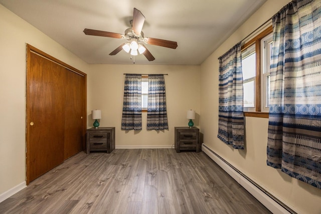 836 Milligan Ave, Wabasha, MN 55981 - bedroom with a baseboard radiator, wood finished floors, baseboards, a closet, and a ceiling fan