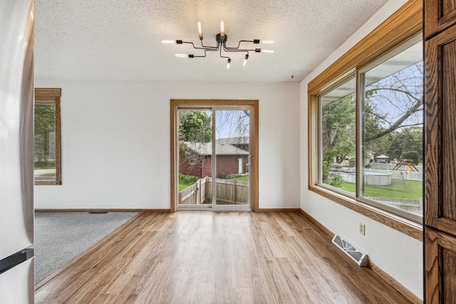 2140 Prospect Dr NE, Saint Cloud, MN 56304 - spare room with a chandelier, light wood-style flooring, a textured ceiling, baseboards, and rail lighting