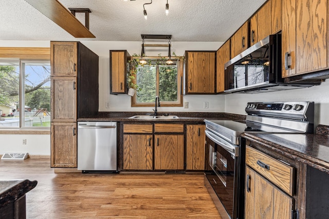 2140 Prospect Dr NE, Saint Cloud, MN 56304 - kitchen featuring appliances with stainless steel finishes, a sink, light wood-style flooring, a textured ceiling, and brown cabinets
